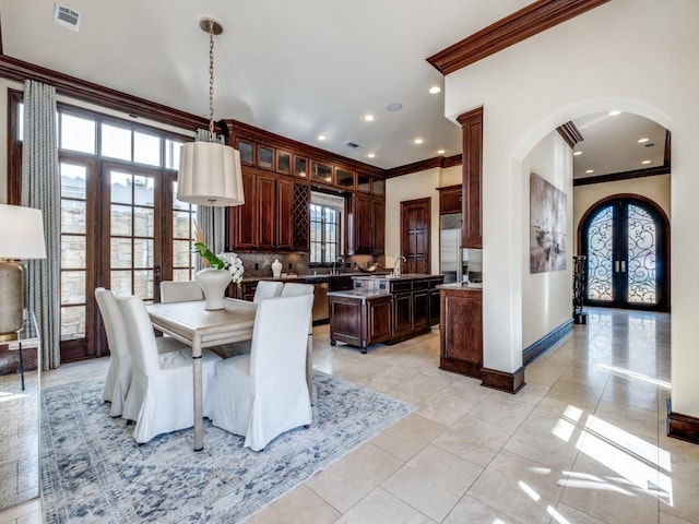 dining space with arched walkways, visible vents, french doors, and crown molding