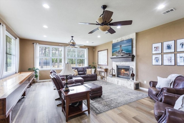 living area featuring baseboards, wood finished floors, visible vents, and a large fireplace