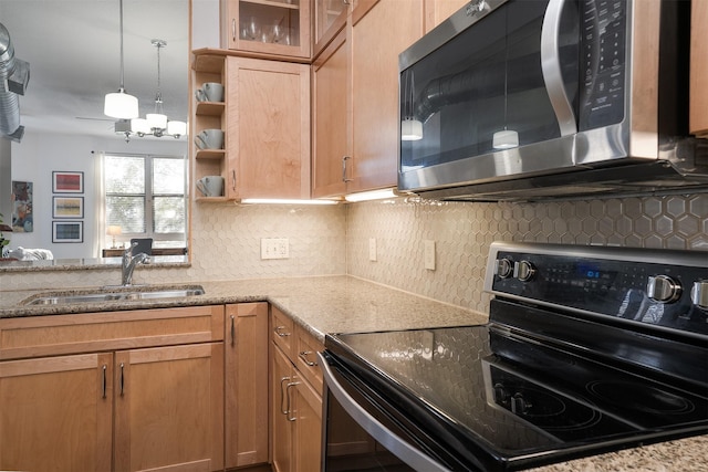 kitchen with light stone counters, a sink, range with electric stovetop, stainless steel microwave, and tasteful backsplash