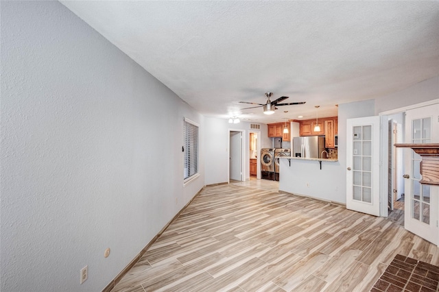 unfurnished living room featuring light wood-type flooring, washer / clothes dryer, and baseboards