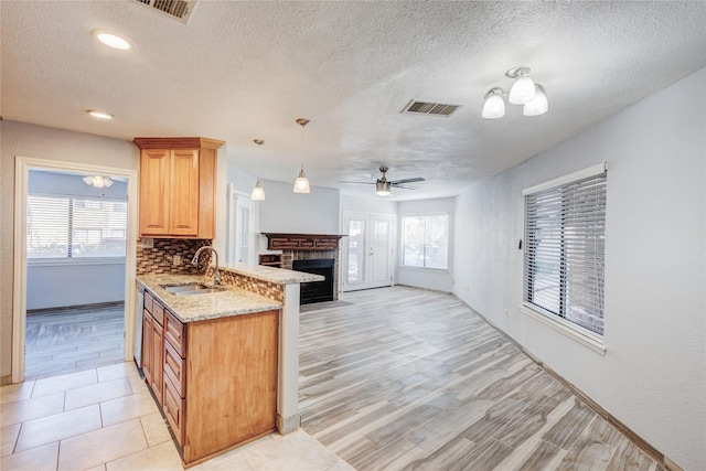 kitchen featuring open floor plan, light stone countertops, visible vents, and a sink