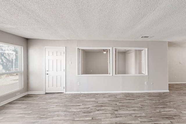 empty room featuring visible vents, wood finished floors, baseboards, and ceiling fan