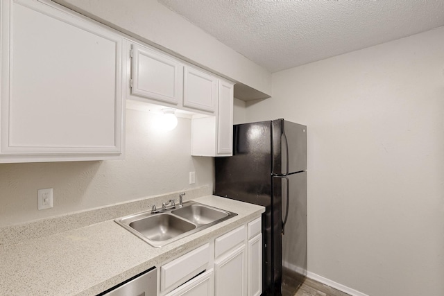 kitchen featuring a sink, a textured ceiling, white cabinets, and light countertops