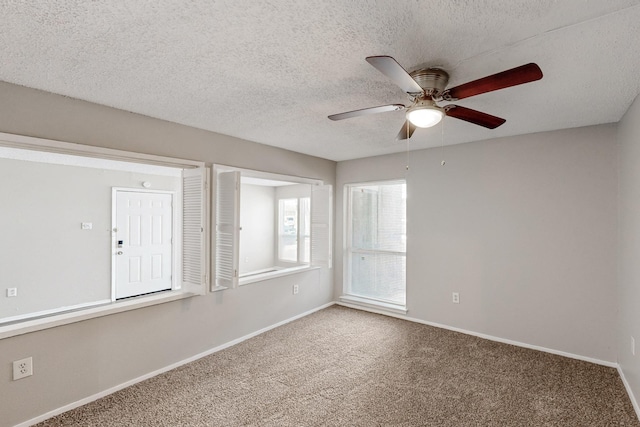 empty room featuring a ceiling fan, baseboards, a textured ceiling, and carpet flooring