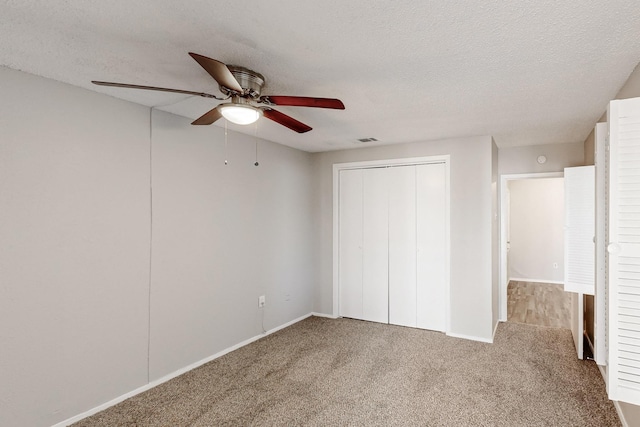 unfurnished bedroom with visible vents, ceiling fan, carpet floors, a closet, and a textured ceiling