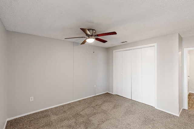 unfurnished bedroom with a closet, visible vents, a textured ceiling, and carpet floors