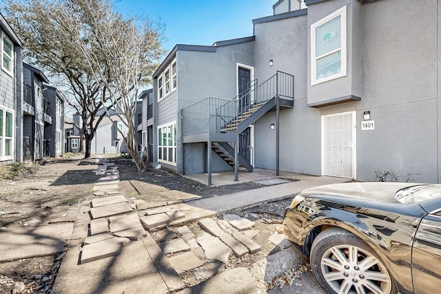 exterior space featuring a patio, stairway, and stucco siding