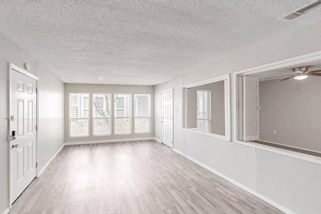 unfurnished sunroom with a ceiling fan and visible vents