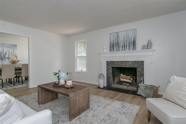 living area with wood finished floors, a fireplace, and baseboards