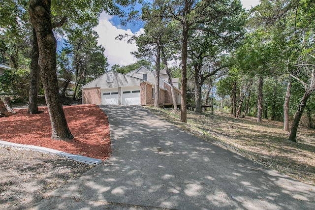 view of front of house with brick siding, an attached garage, and driveway