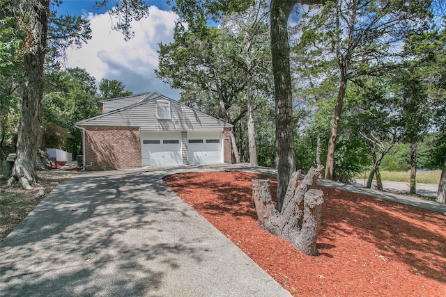 view of front of property featuring an outdoor structure, a garage, brick siding, and driveway