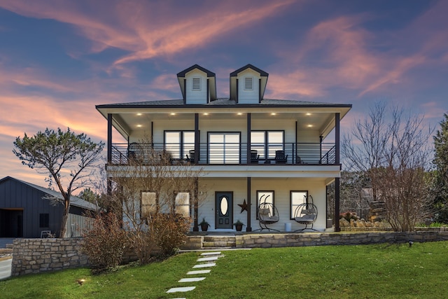 view of front of home with covered porch, a front yard, and a balcony