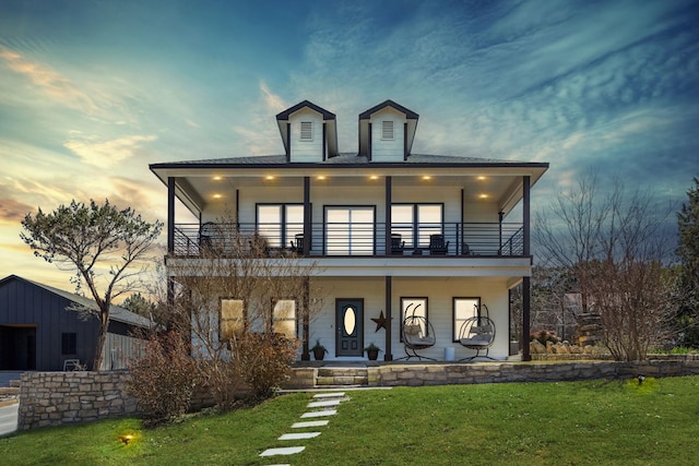 view of front of home featuring a lawn, a porch, and a balcony