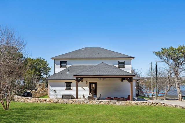 back of property with a lawn, a patio, and roof with shingles