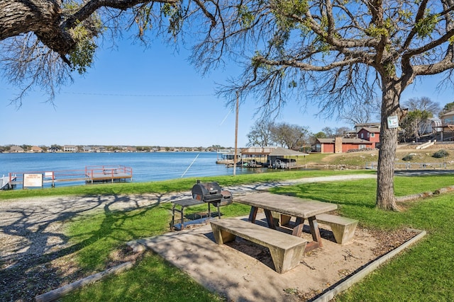 view of property's community featuring a yard, a water view, and a dock