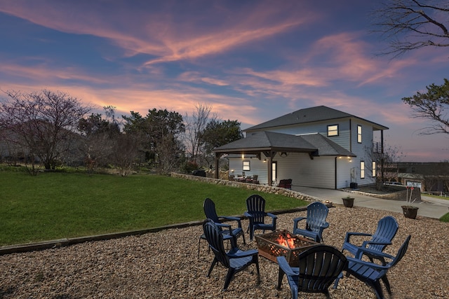 back of property featuring a patio area, a lawn, roof with shingles, and an outdoor fire pit