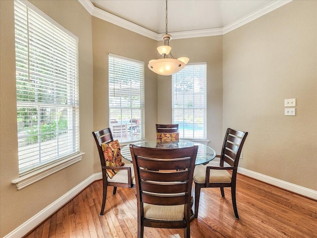 dining space with a healthy amount of sunlight, crown molding, baseboards, and wood-type flooring