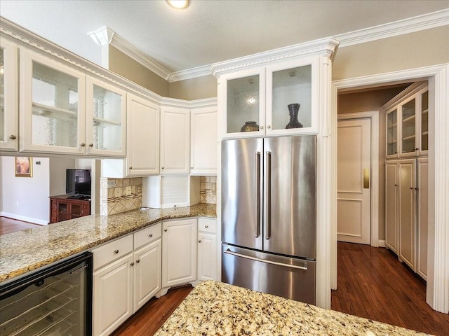 kitchen with wine cooler, light stone counters, dark wood-style flooring, and freestanding refrigerator