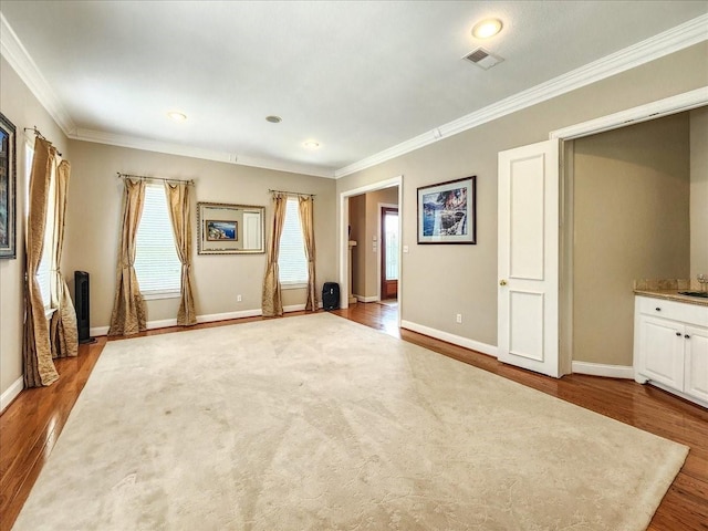 interior space featuring crown molding, baseboards, and wood finished floors