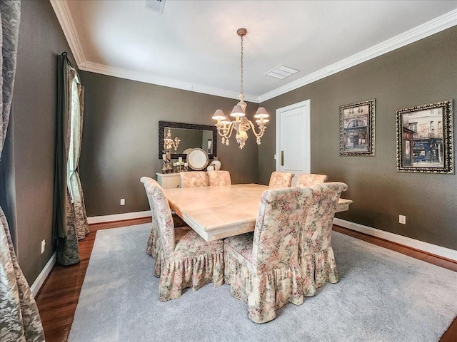 dining room featuring a chandelier, ornamental molding, baseboards, and wood finished floors