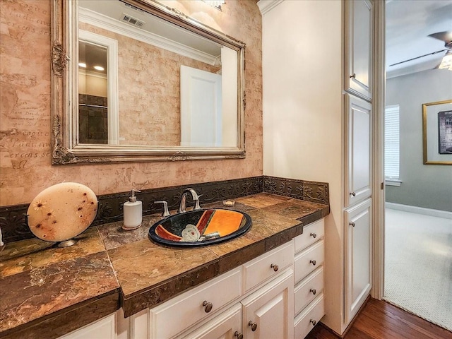 bathroom featuring visible vents, vanity, wood finished floors, and crown molding