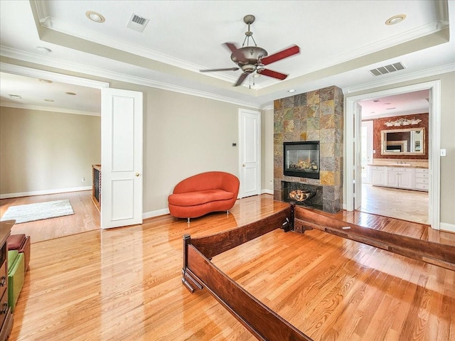 living area with a tray ceiling, visible vents, and a fireplace