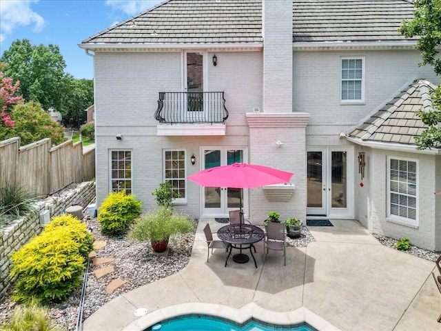 rear view of property featuring french doors, brick siding, and a balcony