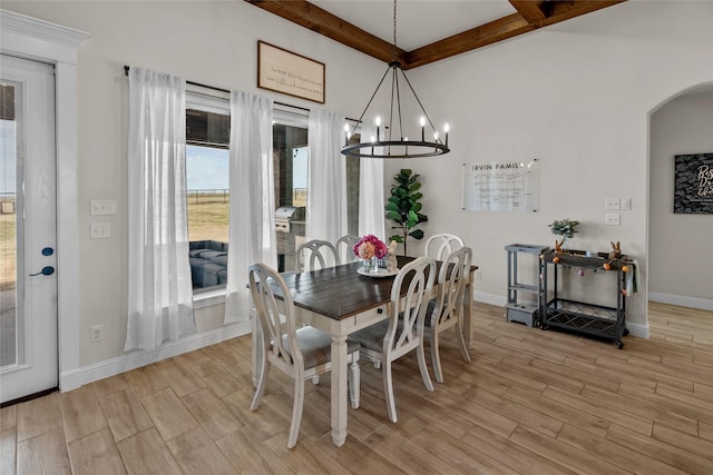 dining space featuring light wood-style flooring, a notable chandelier, beamed ceiling, and arched walkways