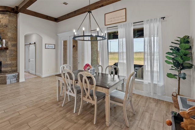 dining room with visible vents, beam ceiling, a barn door, arched walkways, and wood tiled floor