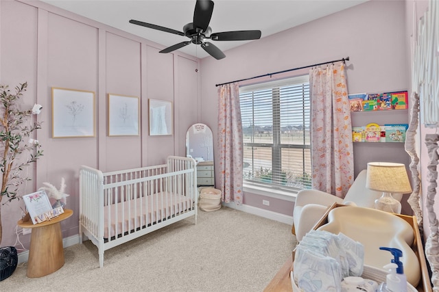 bedroom with ceiling fan, a crib, baseboards, and carpet floors