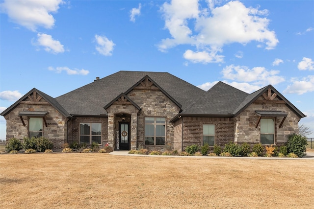 view of front facade featuring a front yard, brick siding, and a shingled roof