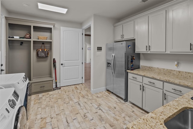 kitchen with light stone countertops, visible vents, baseboards, separate washer and dryer, and stainless steel fridge