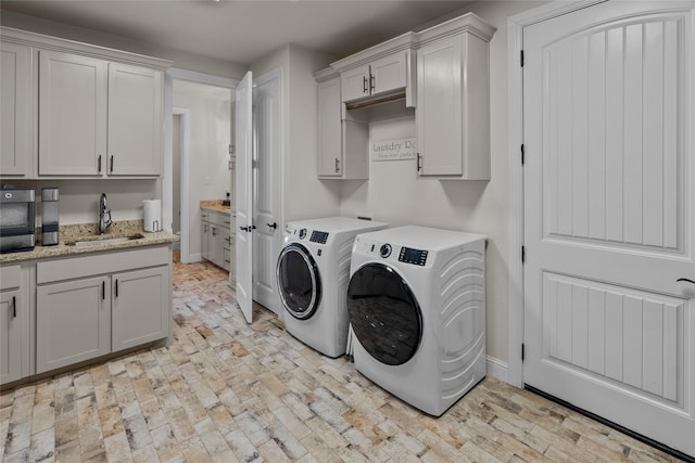 washroom featuring a sink, washing machine and dryer, cabinet space, brick floor, and baseboards