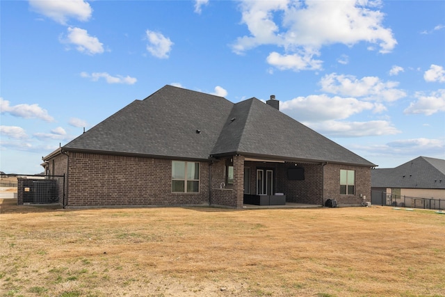 back of house with a lawn, central AC unit, brick siding, and fence