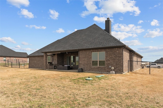 rear view of property with fence, a yard, a chimney, a patio area, and brick siding