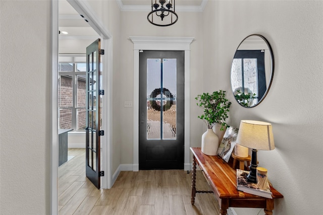 entrance foyer with a wealth of natural light, baseboards, crown molding, and light wood-style floors