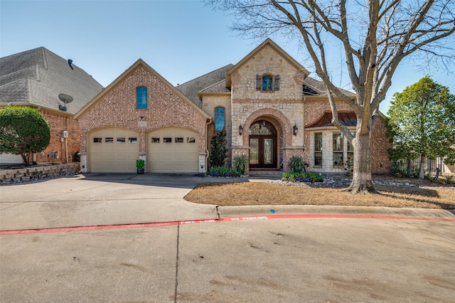 french country style house with french doors, stone siding, brick siding, and an attached garage