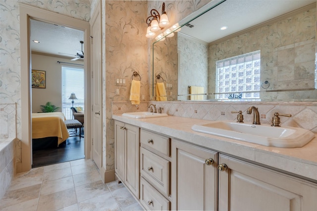 ensuite bathroom with a sink, crown molding, and wallpapered walls