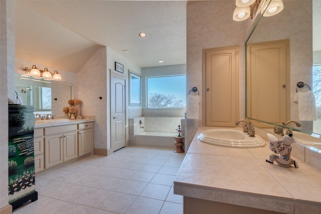 bathroom featuring tile patterned floors, two vanities, a sink, a textured ceiling, and a bath