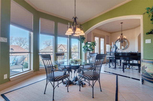 dining area with tile patterned floors, a notable chandelier, crown molding, and arched walkways