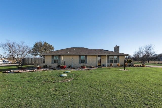 back of property featuring brick siding, a chimney, a yard, and fence