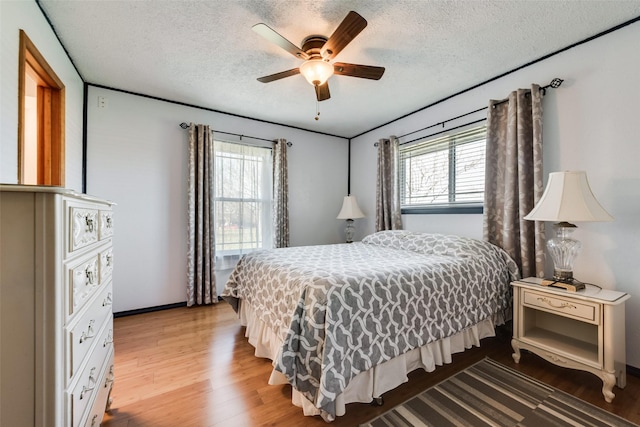 bedroom with multiple windows, a textured ceiling, ceiling fan, and wood finished floors