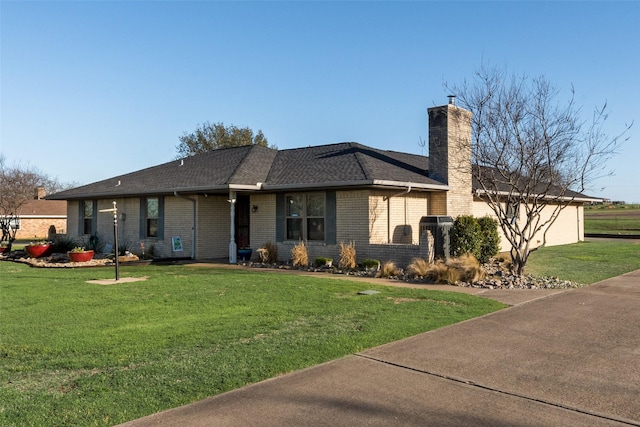 view of front of house with a front lawn, brick siding, roof with shingles, and a chimney