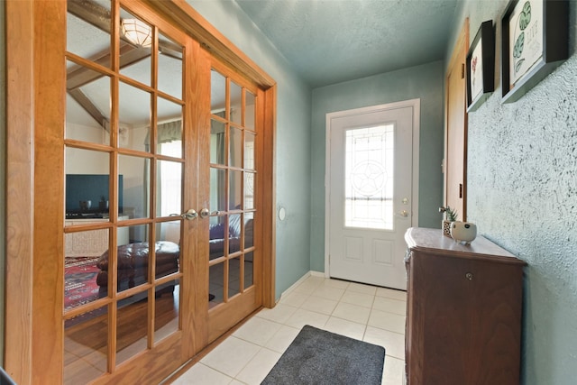 doorway with light tile patterned flooring, french doors, a textured ceiling, and baseboards