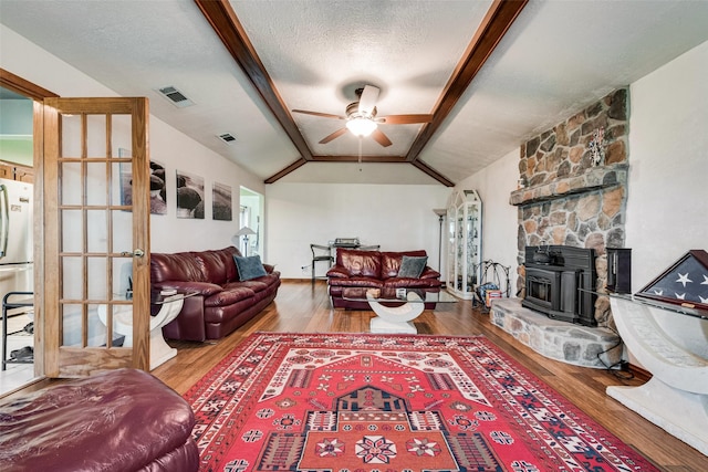 living room with visible vents, lofted ceiling with beams, a textured ceiling, wood finished floors, and ceiling fan