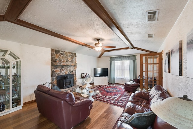 living area with visible vents, a textured ceiling, wood finished floors, and a textured wall