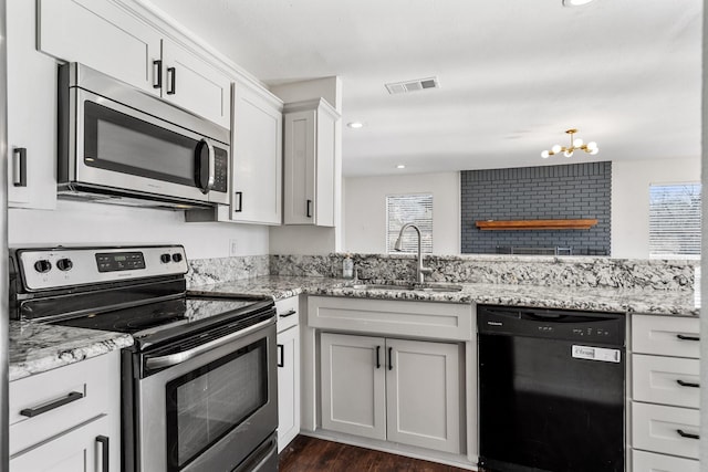 kitchen with light stone counters, visible vents, appliances with stainless steel finishes, and a sink