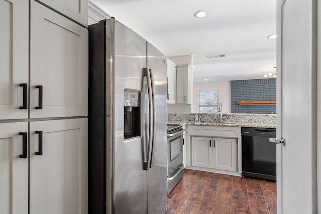 kitchen with light stone countertops, visible vents, dark wood-style flooring, a sink, and appliances with stainless steel finishes