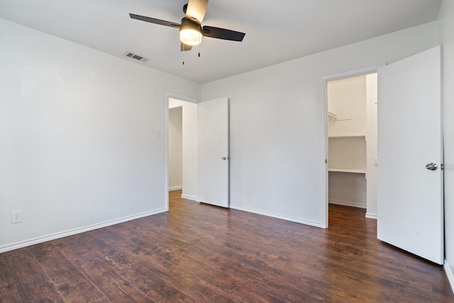 unfurnished bedroom featuring visible vents, baseboards, wood finished floors, and a spacious closet