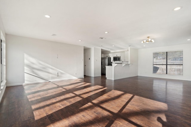 unfurnished living room with an inviting chandelier, dark wood-type flooring, recessed lighting, and baseboards